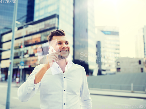 Image of happy man with smartphone calling on city street