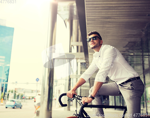 Image of man with bicycle and headphones on city street