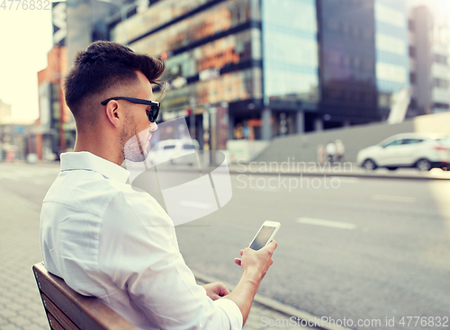 Image of close up of man texting on smartphone in city