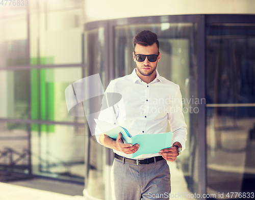 Image of young man with business file on city street