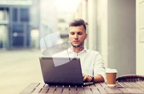 Image of man with laptop and coffee at city cafe