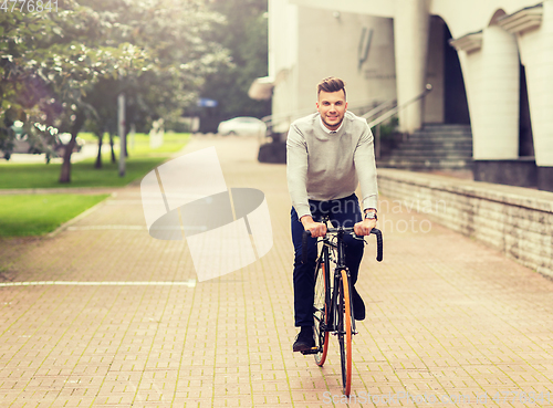 Image of young man riding bicycle on city street