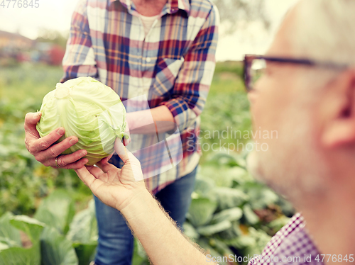 Image of senior couple picking cabbage on farm