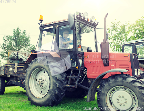 Image of senior man driving tractor at farm