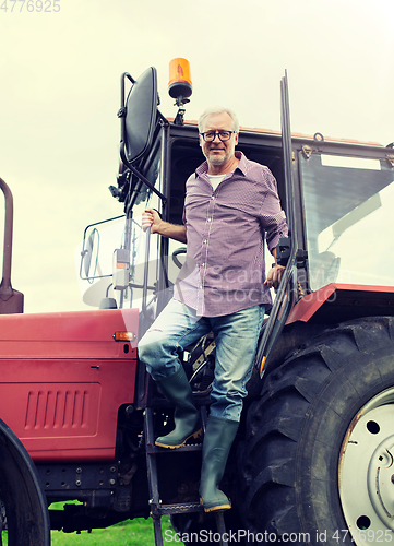 Image of old man or farmer getting out of tractor at farm