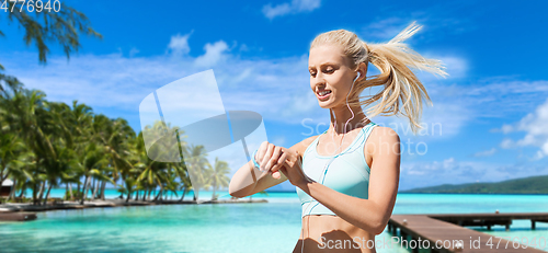 Image of happy woman with fitness tracker and earphones