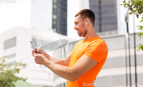 Image of smiling young man with smartphone and earphones