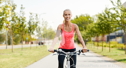 Image of happy young woman riding bicycle outdoors