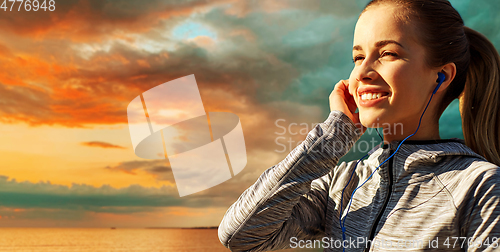 Image of happy couple with earphones running over sea