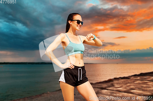 Image of happy woman with fitness tracker on summer beach