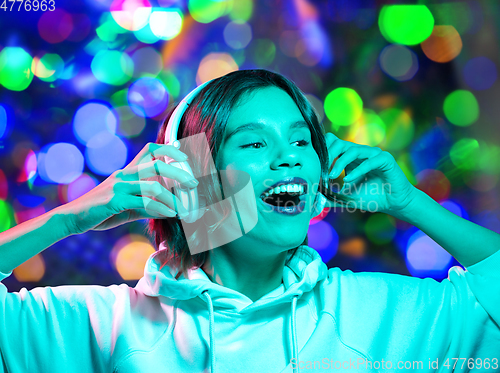 Image of woman in headphones listening to music over lights