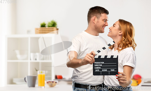 Image of happy couple in white t-shirts with clapperboard