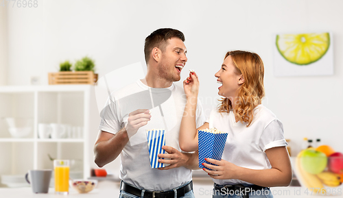 Image of happy couple in white t-shirts eating popcorn