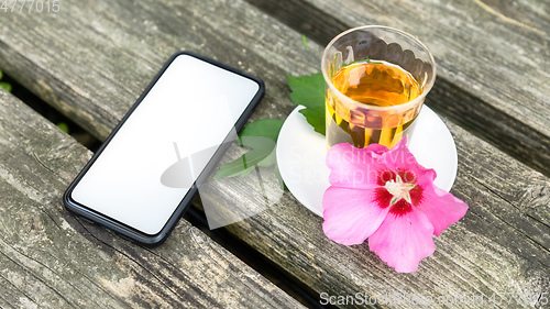 Image of Mallow tea with smartphone on old wooden background