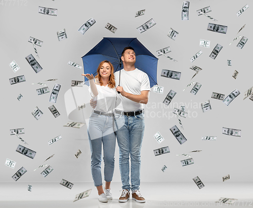 Image of happy couple with umbrella standing money rain