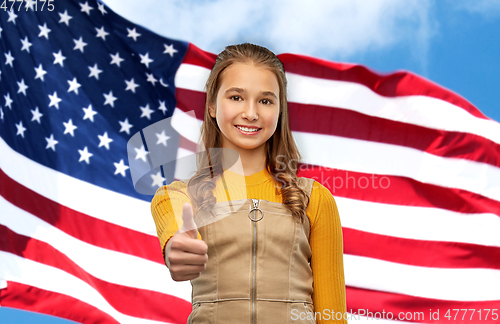 Image of teenage girl showing thumbs up over american flag