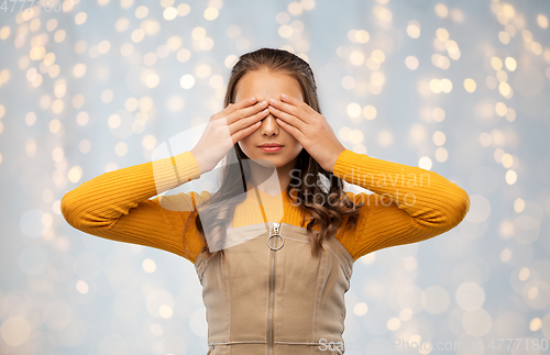 Image of teenage girl closing her eyes by hands