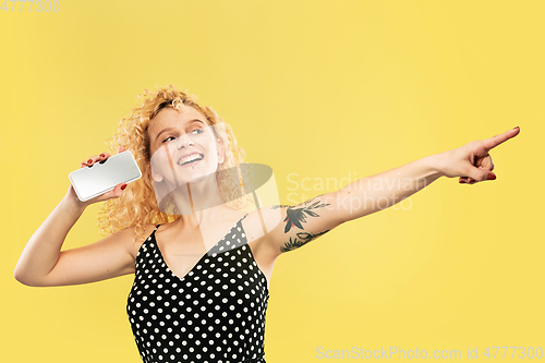 Image of Caucasian young woman\'s half-length portrait on yellow background