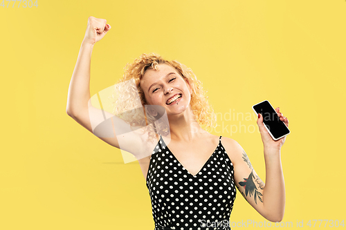 Image of Caucasian young woman\'s half-length portrait on yellow background