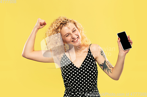 Image of Caucasian young woman\'s half-length portrait on yellow background