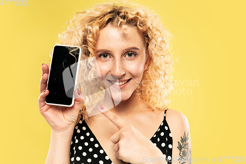 Image of Caucasian young woman\'s half-length portrait on yellow background