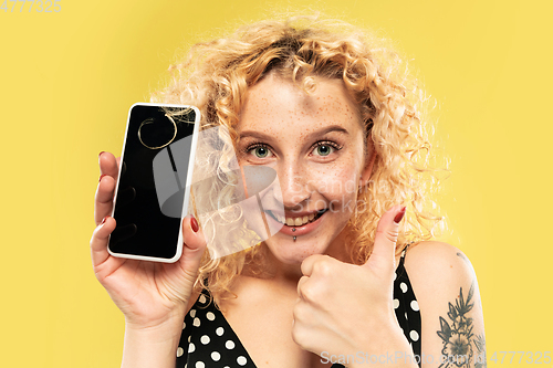 Image of Caucasian young woman\'s half-length portrait on yellow background