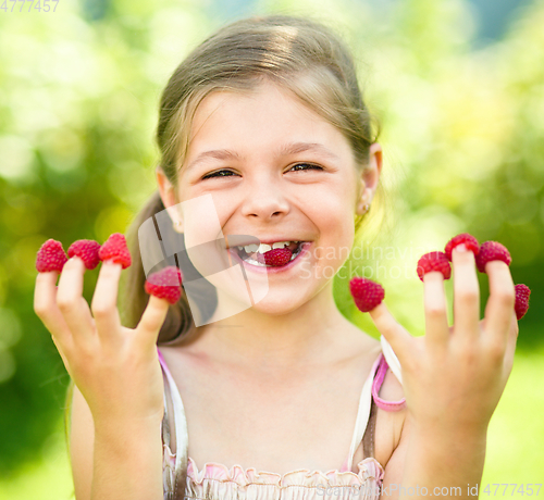 Image of Young girl is holding raspberries on her fingers