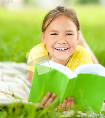 Image of Little girl is reading a book outdoors