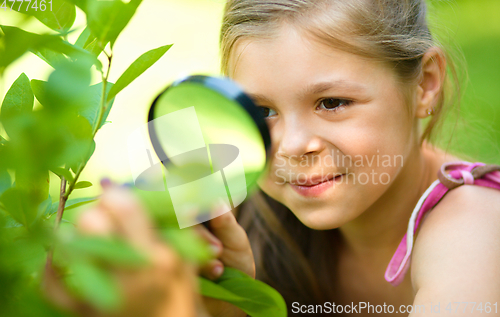Image of Girl is looking at tree leaves through magnifier