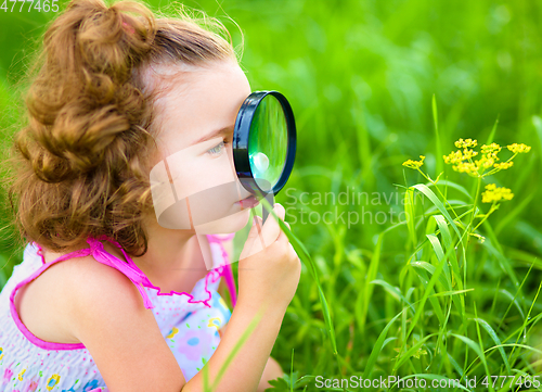 Image of Young girl is looking at flower through magnifier