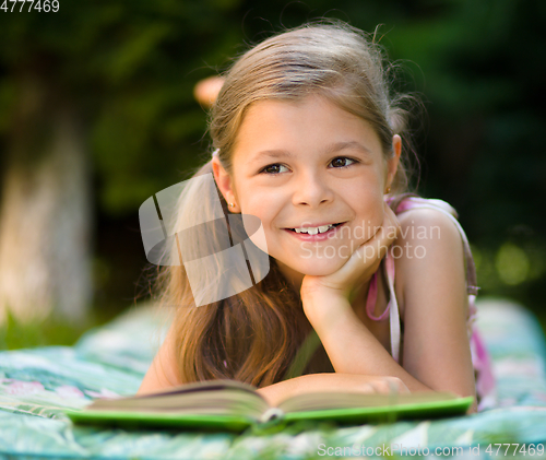 Image of Little girl is reading a book outdoors
