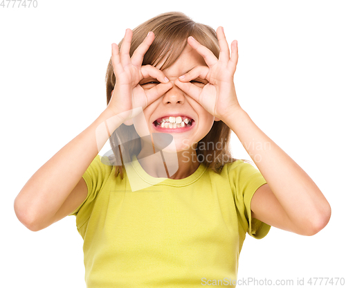 Image of Happy little girl is showing glasses gesture