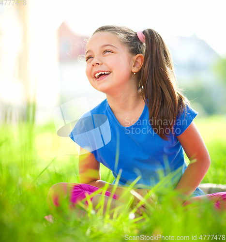 Image of Portrait of a little girl sitting on green grass