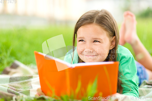Image of Little girl is reading a book outdoors