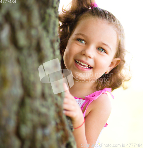 Image of Cute little girl is playing hide and seek