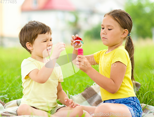 Image of Little girl and boy are blowing soap bubbles