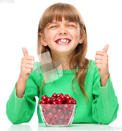 Image of Cute girl is eating cherries showing thumb up sigh