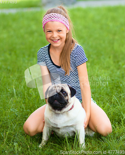 Image of Little girl and her pug dog on green grass