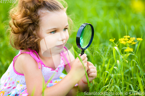 Image of Young girl is looking at flower through magnifier