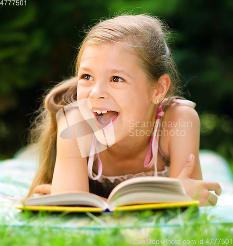 Image of Little girl is reading a book outdoors