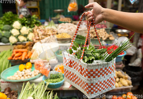 Image of Hand holding basket with vegetable in wet market 