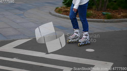 Image of Feet of girl riding on a roller skates ride on asphalt.