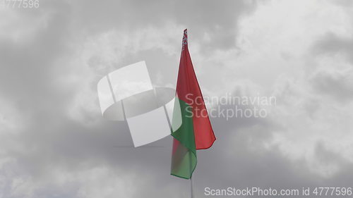 Image of Belarus flag on the flagpole waving in the wind against a blue sky with clouds. Slow motion