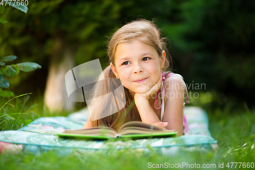 Image of Little girl is reading a book outdoors