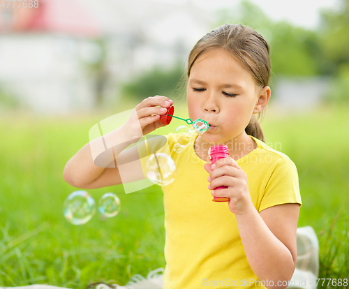 Image of Little girl is blowing a soap bubbles