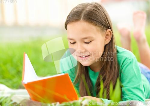 Image of Little girl is reading a book outdoors