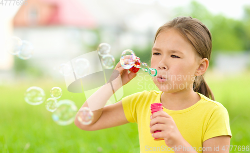 Image of Little girl is blowing a soap bubbles