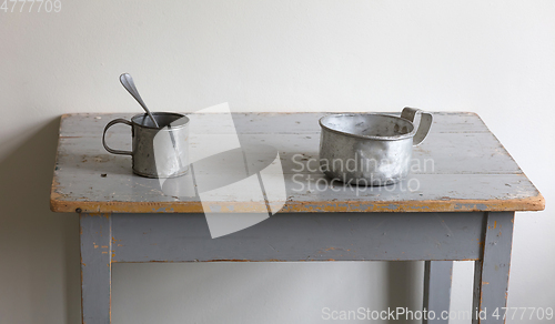 Image of Very old metal cups and plates on a wooden table