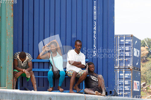 Image of Malagasy peoples resting in the shadow of the containers in Nosy