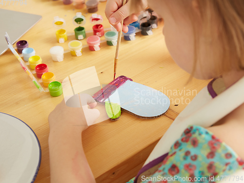 Image of Cute little girl painting on home interior background